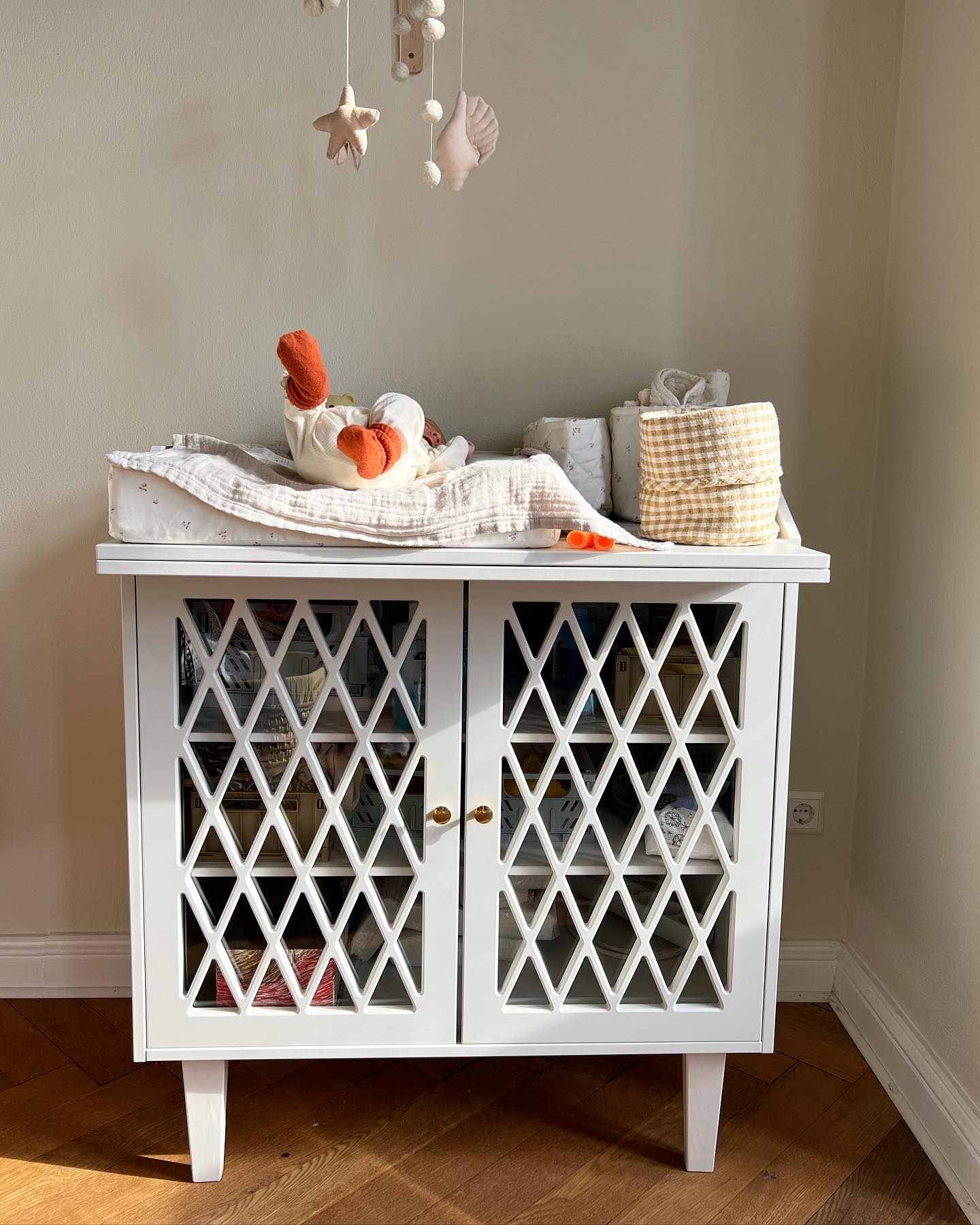 Ich hatte fast ein schlechtes Gewissen, weil wir bis zum Tag von Gustavs Geburt noch immer kein eingerichtetes Kinderzimmer aus dem Hut gezaubert hatten, ganz bewusst nicht, mit voller Absicht also. Und das, wo wir ehrlich gesagt doch sonst so viel im Überfluss haben und das Internet sich fast verschluckt an all den Bildern vollgepackter Räume und Regale nur für winzig kleine Menschen. Stattdessen steht hier eine Wickelkommode von @camcam_cph (gifted) gleich neben unserem Bett, mit ein paar Klappkästchen von @kindsgut drin, in denen zwei Strampler von @liewood_design liegen, drei Wolle-Seide-Bodies und dazu drei Höschen plus Mützchen, Mulltücher, ein Teddy vom großen Bruder, eine Babytrage, eine Decke aus Schurwolle von @hessnatur, ein gemütlicher Schlafsack, warme Söckchen. Waschlappen, ein Nachtlicht und eine Handvoll Klimbim mit Ringeln und Herzen drauf. Daneben steht ein gebrauchter Stubenwagen, das Moseskörbchen, in dem Gus den halben Tag verbringt und irgendwo hängt außerdem so eine supermoderne Wunderwiege, das war’s. Und ich finde, das ist schon richtig, richtig viel. Mehr als die meisten haben sowieso. Genug für den Anfang  Viele von euch haben danach gefragt, nach dieser ersten Ausstattung, und deshalb hoffe ich, dass ich nichts vergessen habe. Kann aber schon sein, weil naja🙃 (Anzeige weil Markennennung)